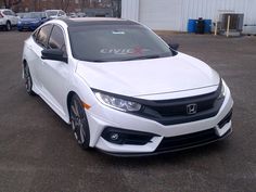 a white honda civic is parked in a parking lot