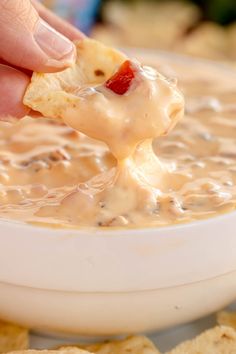 a person dipping cheese into a bowl of dip