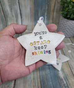 a hand holding a ceramic star ornament that says, you're a star keep shining