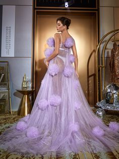 a woman in a purple dress is standing on a stage with her hands behind her back