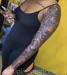 a woman with tattoos on her arm holding a cell phone