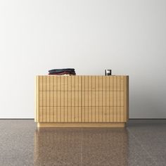 an empty room with a wooden cabinet on the floor and a black object sitting on top of it