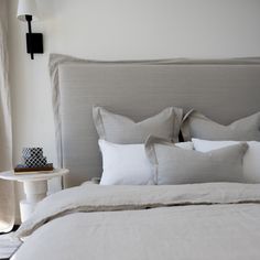 a bed with white linens and pillows on top of it next to a night stand