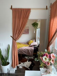 a bed room with a neatly made bed next to a potted plant and window