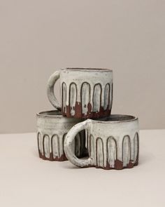 three white and brown mugs stacked on top of each other with chocolate drizzle