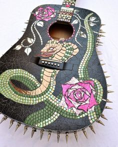 a guitar decorated with flowers and spikes