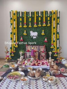 a table topped with lots of food next to a wall covered in flowers and decorations