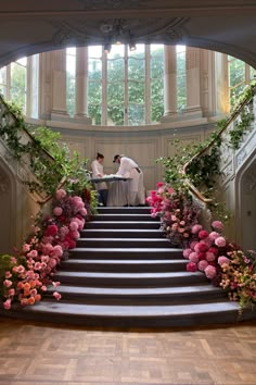 two people sitting at the top of a set of stairs with flowers on each step