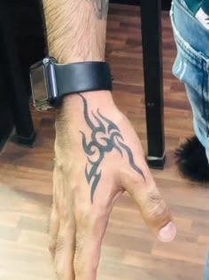 a man's hand with a tattoo on it and a black wristband around his wrist