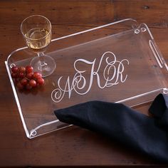 a wine glass and some grapes on a wooden table with a personalized serving tray