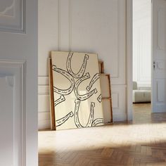 an empty room with two paintings on the floor and one is leaning up against the wall