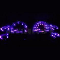 two speedometers in the dark with blue lights on them, all lit up