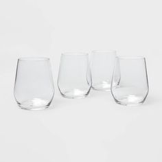 four glasses sitting next to each other on a white surface with one empty glass in the middle