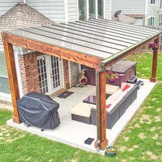 a covered patio with couches and an umbrella on the back deck in front of a house