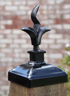 a black metal bird on top of a wooden post