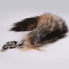 a furry animal tail with scissors attached to it's side on a white surface