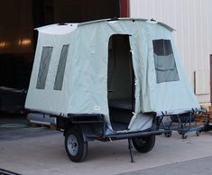 a trailer with a tent attached to the back is parked in front of a building