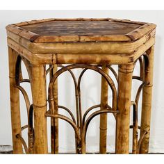 an old bamboo table with wicker and leather top is shown in front of a white wall