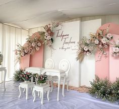 a table and chairs are set up in front of a wall with flowers on it