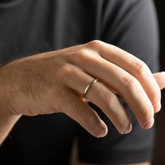 a man wearing a gold wedding band is holding his hand out to the other side