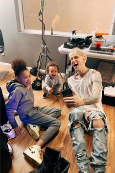 two young children sitting on the floor with their mouths open and one child holding an electronic device