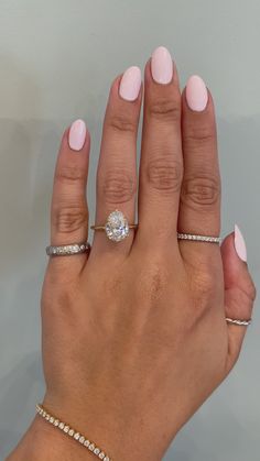 a woman's hand with pink manicured nails and two rings on her fingers