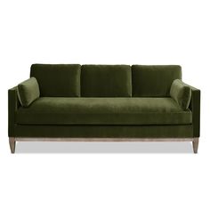 a green velvet couch with wooden legs