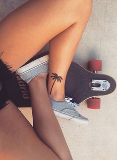 a woman with a small tattoo on her left leg sitting next to a skateboard