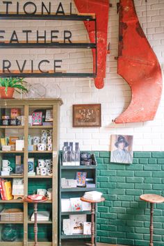 the interior of a store with green brick walls and shelves filled with books, magazines and other items