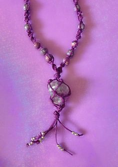 a purple beaded necklace with beads and charms hanging from it's end on a purple background