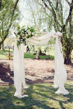 an outdoor ceremony setup with white drapes and flowers