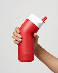 a hand holding a red and white insulated water bottle with a straw in it