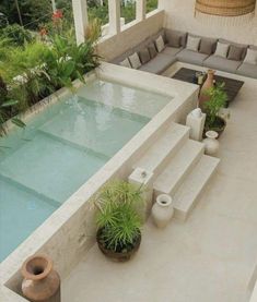 an outdoor living area with couches and plants next to a swimming pool in the middle