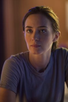 a woman sitting at a table with a plate of food in front of her and looking off to the side