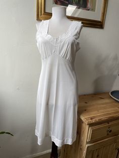 This is such a classic, pretty little slip dress or nightgown, in 100% white nylon with delicate lace details at the straps, bust, and hem. In excellent vintage condition. Marked as a UK size 16 (see photos for measurements) but I'd say it's closer to a modern UK 10-12. All items listed in Attic 1 Shop are vintage and pre-owned/pre-worn unless explicitly stated in the listing. Please be aware that this means items are not in brand new condition and you must read item descriptions thoroughly to e Summer Sleeveless Nightgown With Lace Trim, Sleeveless Summer Nightgown With Lace Trim, Sleeveless Lace Trim Nightgown For Summer, Midi Length Slip Dress With Lace Trim For Daywear, Feminine Midi Slip Dress With Lace Trim, Camisole Dress With Lace Trim For Daywear, Daywear Camisole Dress With Lace Trim, Feminine Midi Length Slip Dress With Lace Trim, Summer Nightgown With Spaghetti Straps And Lace Trim