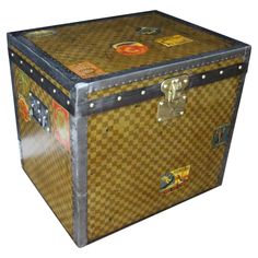 an old trunk is covered with stickers and has metal trim around the bottom part