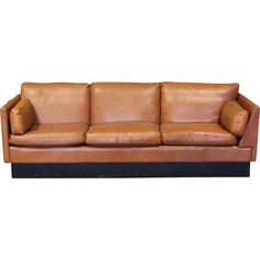 a brown leather couch with two pillows on the back and one arm folded over it