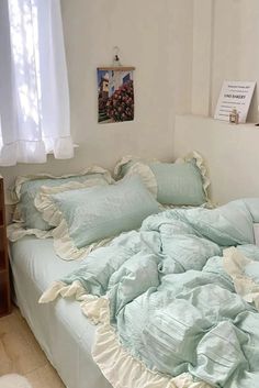 an unmade bed with blue sheets and pillows