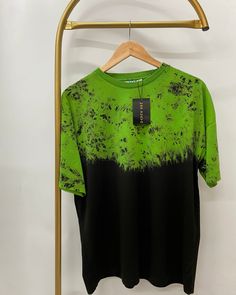 a green and black t - shirt hanging on a clothes rack