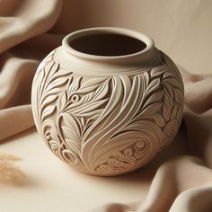 a white vase sitting on top of a table next to a brown feathery object