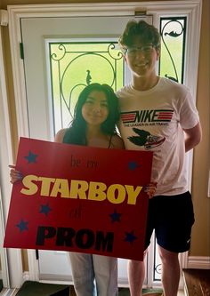 two people standing in front of a door holding a sign that says starboy at prom