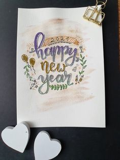 two paper hearts are next to a card with the words happy new year written on it