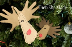 two handprinted reindeer ornaments hanging from a christmas tree