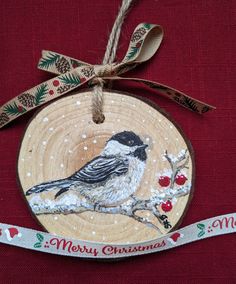 a wooden ornament with a bird on it and ribbon hanging from the front