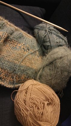 two balls of yarn sitting next to each other on top of a blue blanket with knitting needles