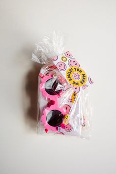 some pink and black sunglasses in a plastic bag on a white surface with an animal sticker