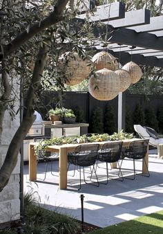 an outdoor dining area with chairs, table and hanging baskets on the ceiling above it