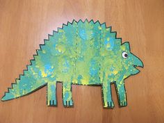 a paper cut out of a green dinosaur