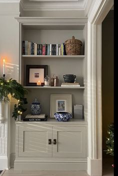 a white book shelf with christmas decorations and candles on it in the corner of a room