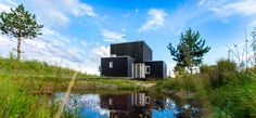 a small building sitting on top of a lush green field next to a lake and forest